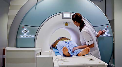 A person in an MRI machine being tened by a technician
